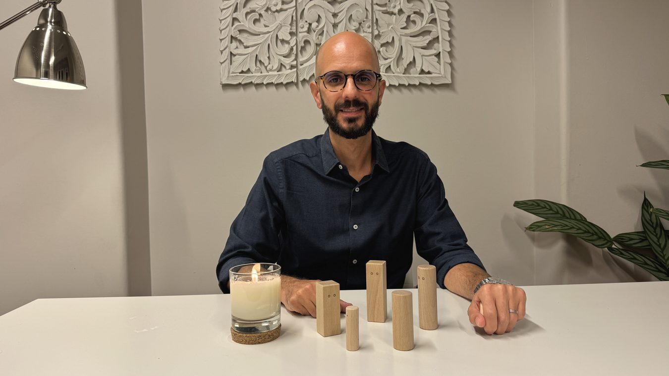 Rodrigo Justo à mesa de trabalho, com a vela e as figuras da sessão.